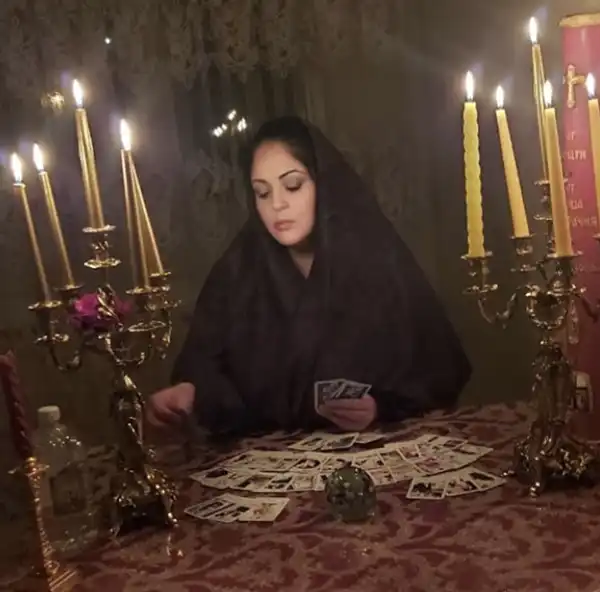 Гадалка Алёна проводит обряд отливания воском на картах Таро при свечах — эзотерический ритуал очищения и предсказания будущего